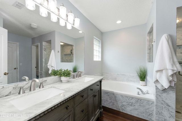 bathroom featuring vanity, independent shower and bath, a textured ceiling, and hardwood / wood-style floors