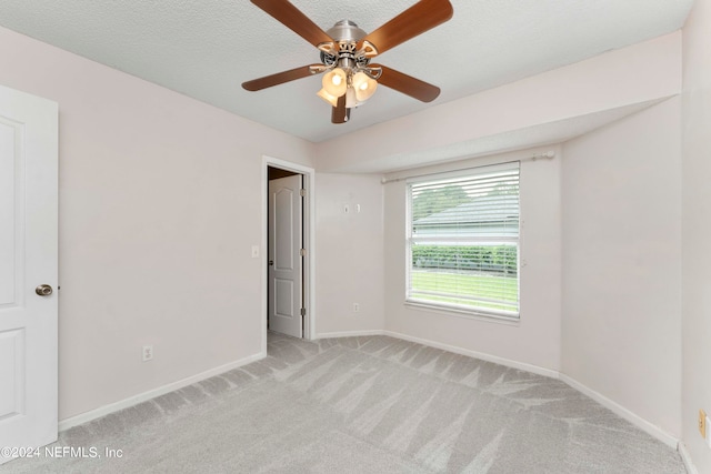 unfurnished room with a textured ceiling, light colored carpet, and ceiling fan