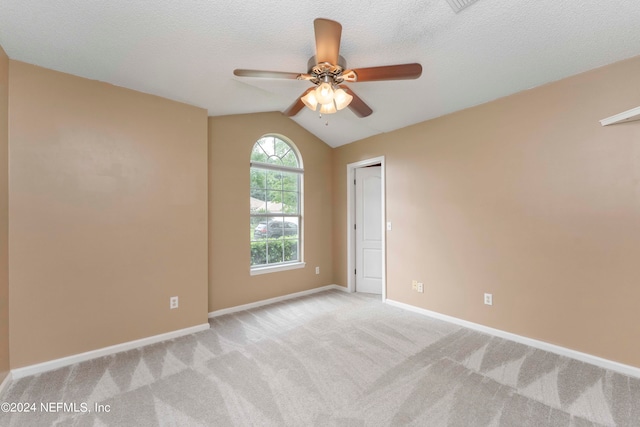 carpeted empty room featuring vaulted ceiling, a textured ceiling, and ceiling fan