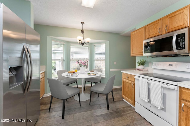 kitchen featuring dark hardwood / wood-style flooring, appliances with stainless steel finishes, an inviting chandelier, a textured ceiling, and pendant lighting