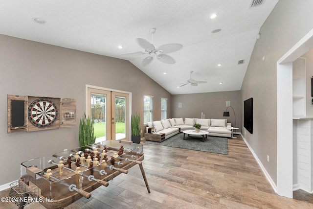 living room with lofted ceiling, ceiling fan, a textured ceiling, light wood-type flooring, and french doors