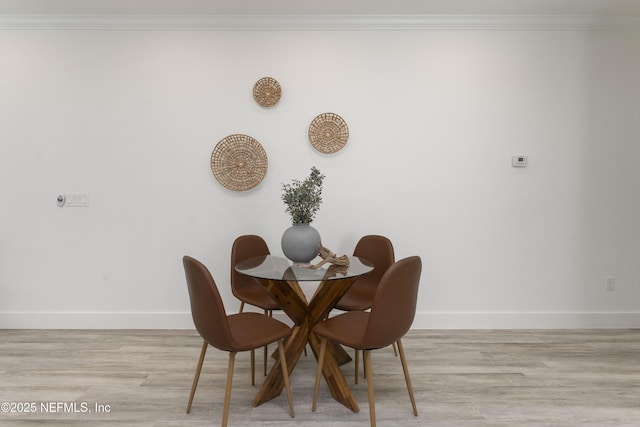 dining space featuring light hardwood / wood-style flooring and crown molding