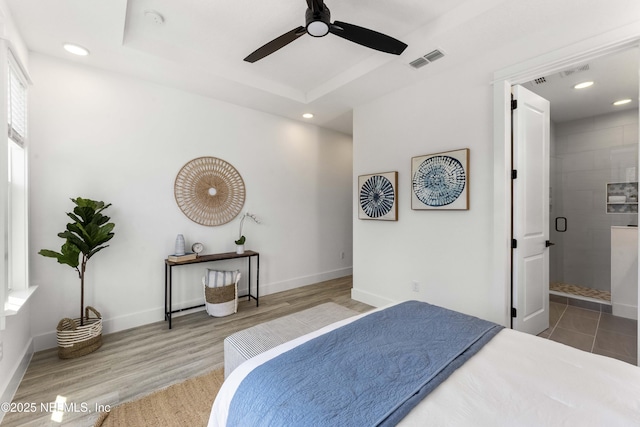 bedroom with hardwood / wood-style floors, a tray ceiling, and ceiling fan