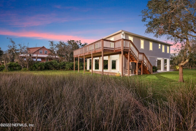 back house at dusk with a lawn and a wooden deck