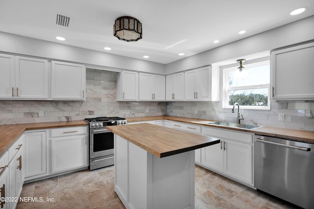 kitchen featuring wooden counters, a kitchen island, white cabinets, appliances with stainless steel finishes, and sink