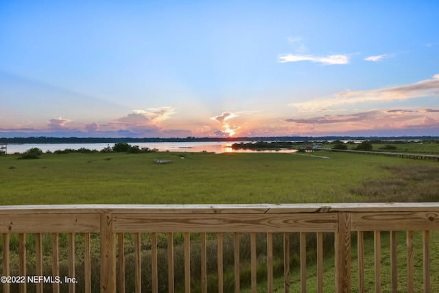 yard at dusk featuring a rural view and a water view