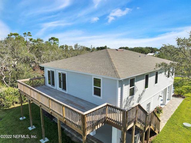 rear view of property featuring a wooden deck and a lawn