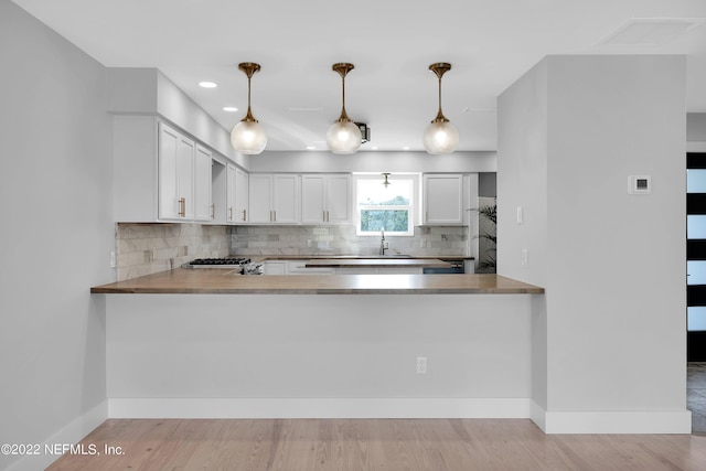 kitchen with decorative backsplash, decorative light fixtures, white cabinetry, and kitchen peninsula