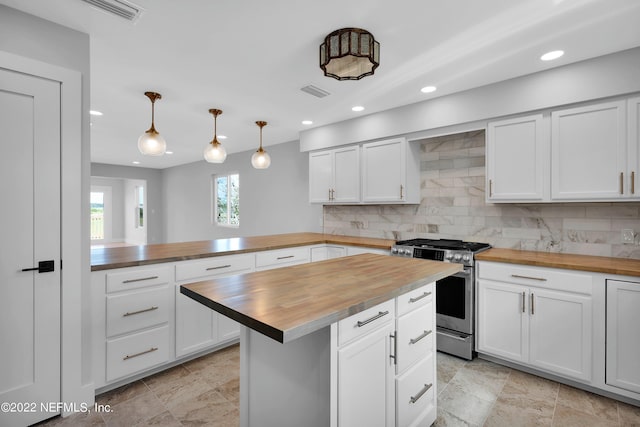 kitchen with kitchen peninsula, stainless steel gas range oven, pendant lighting, white cabinetry, and butcher block counters