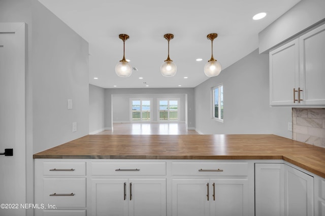 kitchen with hanging light fixtures, white cabinetry, wood counters, and tasteful backsplash