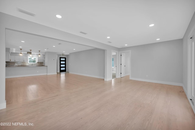 unfurnished living room featuring sink and light wood-type flooring