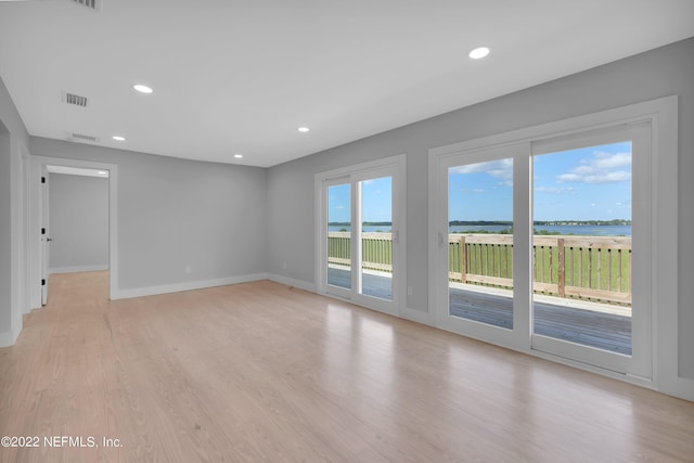 empty room with light hardwood / wood-style flooring and plenty of natural light