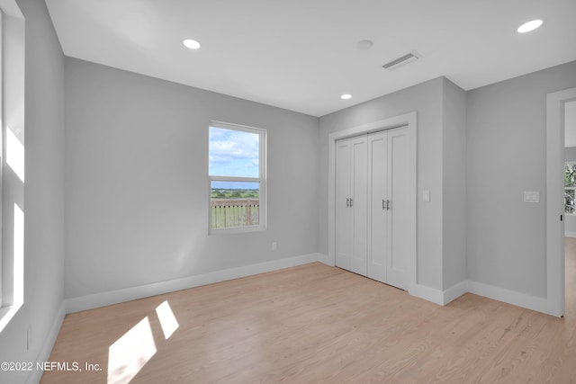 unfurnished bedroom featuring light wood-type flooring and a closet