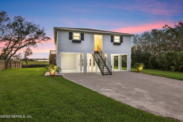 back house at dusk with a yard and a carport