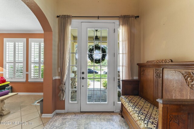 doorway with light tile patterned floors and ornamental molding