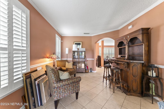 living area featuring light tile patterned flooring, a textured ceiling, and ornamental molding