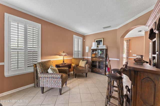 sitting room featuring a textured ceiling, a wealth of natural light, light tile patterned floors, and ornamental molding