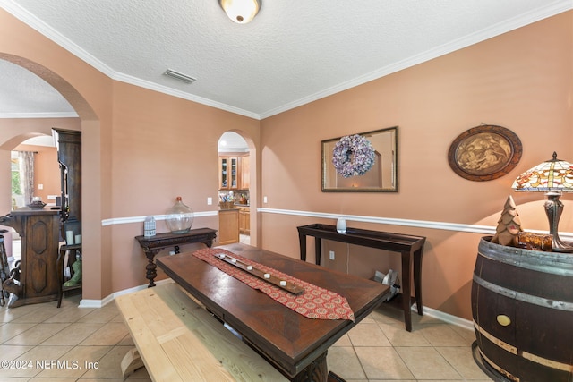 dining room with ornamental molding, light tile patterned floors, and a textured ceiling