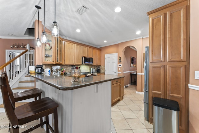 kitchen with light tile patterned flooring, dark stone counters, backsplash, appliances with stainless steel finishes, and pendant lighting