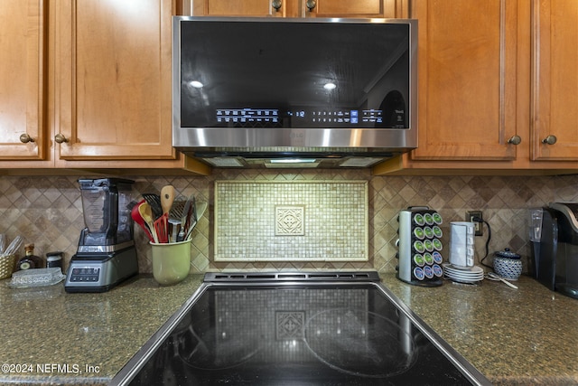 kitchen with dark stone countertops and tasteful backsplash