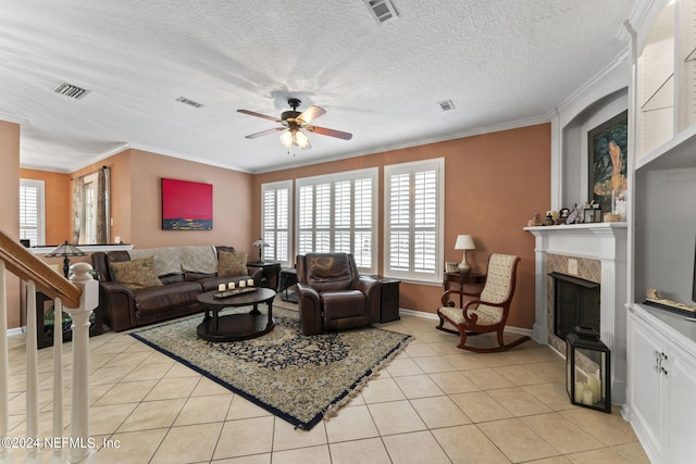 tiled living room with a textured ceiling, ornamental molding, a premium fireplace, and ceiling fan