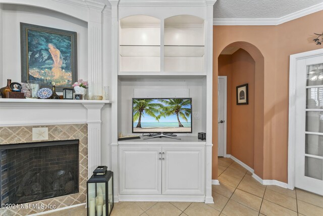 living room featuring ornamental molding, a tiled fireplace, light tile patterned floors, and a textured ceiling