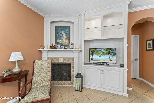 tiled living room with a tile fireplace, crown molding, and a textured ceiling