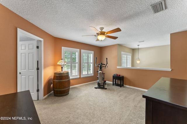 sitting room featuring light carpet, ceiling fan, and a textured ceiling