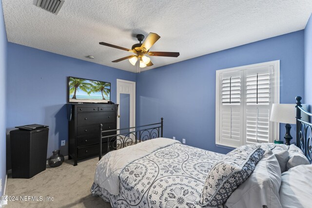 bedroom with light carpet, ceiling fan, and a textured ceiling