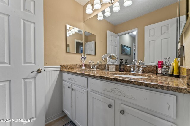 bathroom with a textured ceiling, tile patterned floors, and double sink vanity