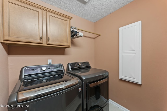 laundry area with cabinets, washing machine and dryer, and a textured ceiling