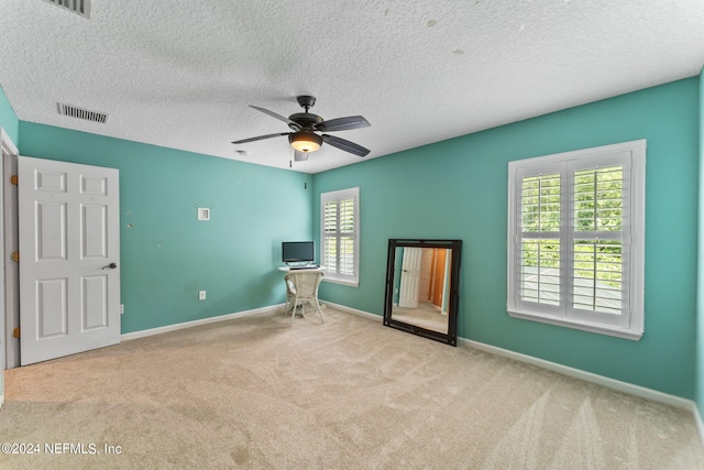 unfurnished bedroom featuring light carpet, a textured ceiling, and ceiling fan