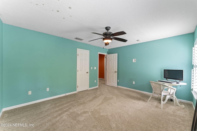 unfurnished office with light carpet, a textured ceiling, and ceiling fan