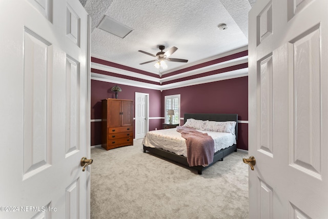 bedroom featuring ceiling fan, crown molding, light carpet, and a tray ceiling