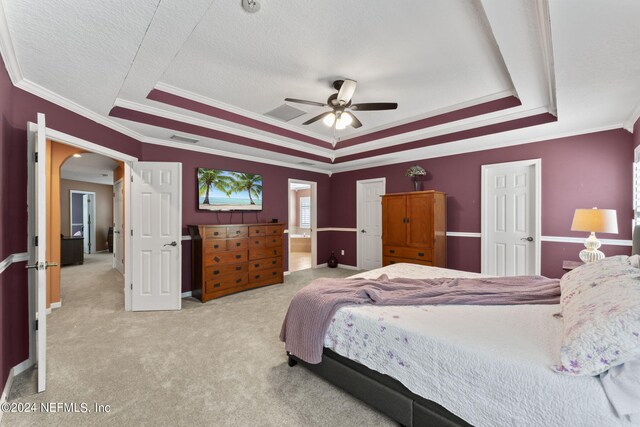 bedroom featuring ceiling fan, a tray ceiling, and light colored carpet