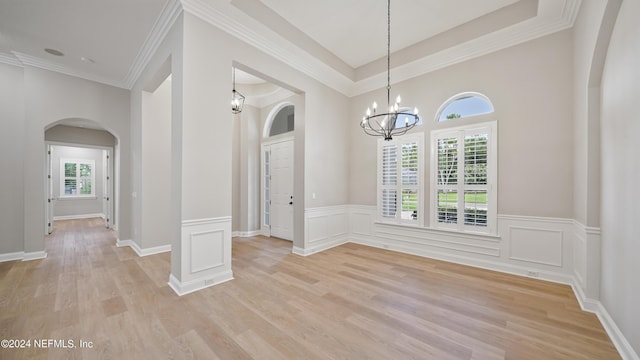 spare room with light wood-type flooring, a wealth of natural light, and a chandelier