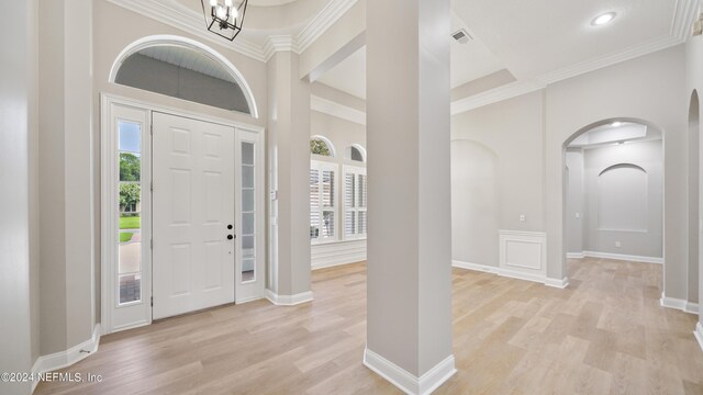 entryway with a chandelier, light wood-type flooring, and ornamental molding