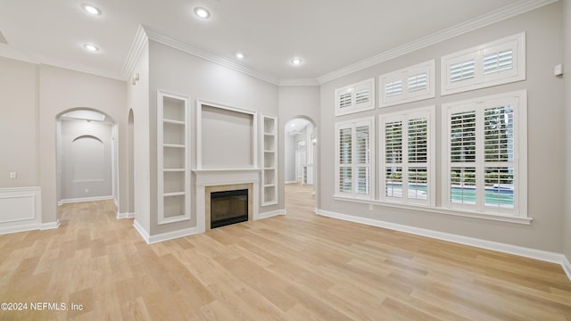 unfurnished living room featuring light hardwood / wood-style flooring, built in features, and crown molding