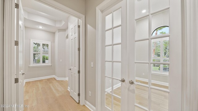 corridor with light hardwood / wood-style flooring and french doors