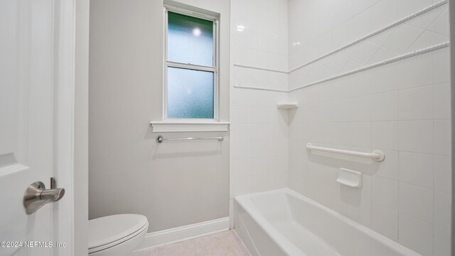 bathroom featuring tile patterned flooring, toilet, and tiled shower / bath