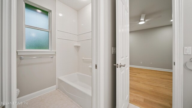 bathroom with hardwood / wood-style floors, ceiling fan, toilet, and shower / tub combination