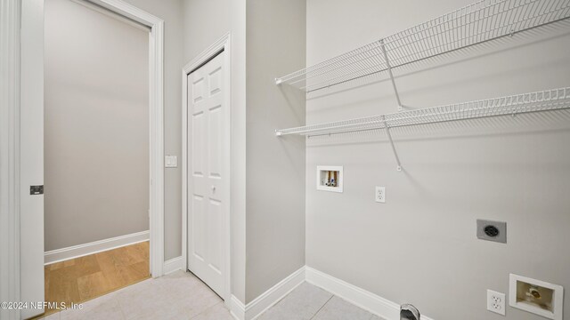 clothes washing area featuring electric dryer hookup, hookup for a washing machine, and light tile patterned floors