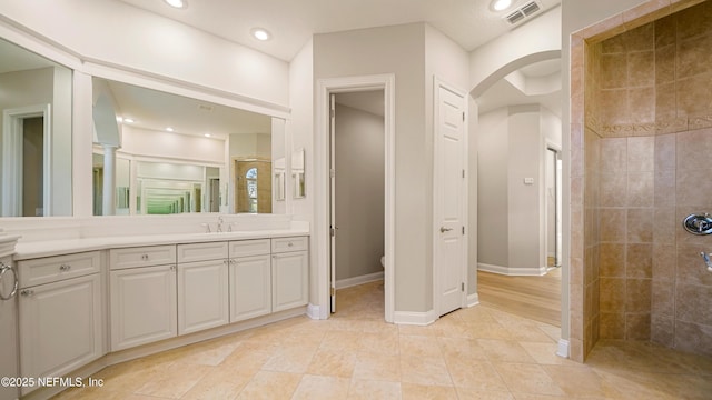 bathroom with tiled shower, tile patterned floors, vanity, and toilet