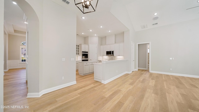 kitchen with kitchen peninsula, light hardwood / wood-style flooring, white cabinets, and stainless steel appliances