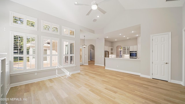 unfurnished living room with ceiling fan, high vaulted ceiling, and light hardwood / wood-style flooring