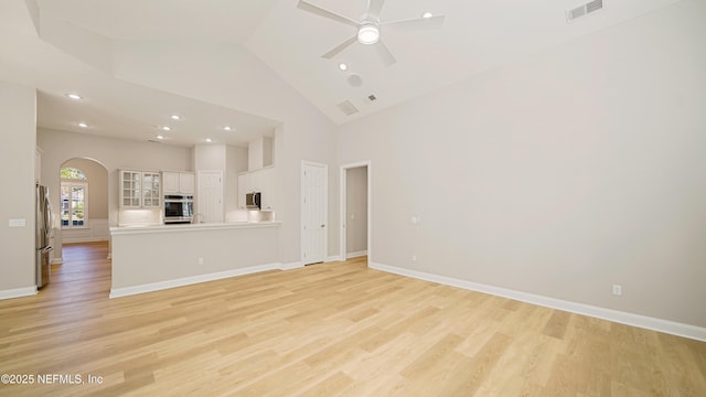 unfurnished living room with ceiling fan, a high ceiling, and light wood-type flooring