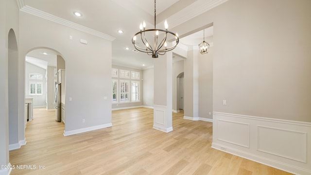 unfurnished dining area with ornate columns, light hardwood / wood-style floors, a chandelier, and ornamental molding