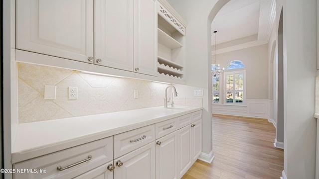 kitchen featuring pendant lighting, light hardwood / wood-style floors, white cabinetry, and sink