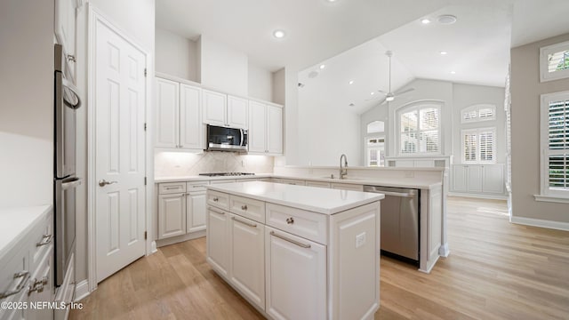 kitchen with white cabinets, ceiling fan, a kitchen island, and appliances with stainless steel finishes