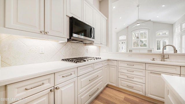 kitchen featuring ceiling fan, stainless steel appliances, vaulted ceiling, white cabinets, and light wood-type flooring